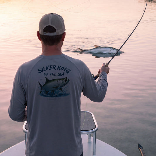 Silver King performance shirt in grey, casting to a rolling tarpon from the bow of a flats skiff at sunrise