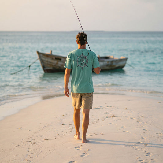 Not All Who Wander Are Lost tee in seafoam, walking a sandbar toward a skiff