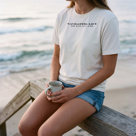 One Wave at a Time tee in ivory, morning coffee on a beach boardwalk